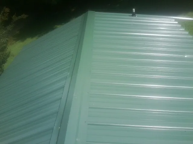 New green metal panels meeting at the ridge of a roof — Flat Roof Repair work by our crew in Sandown