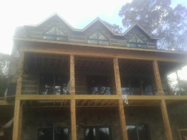 Dormers and porch framing on a large log home under construction — Roof Coating work by our crew in Sandown