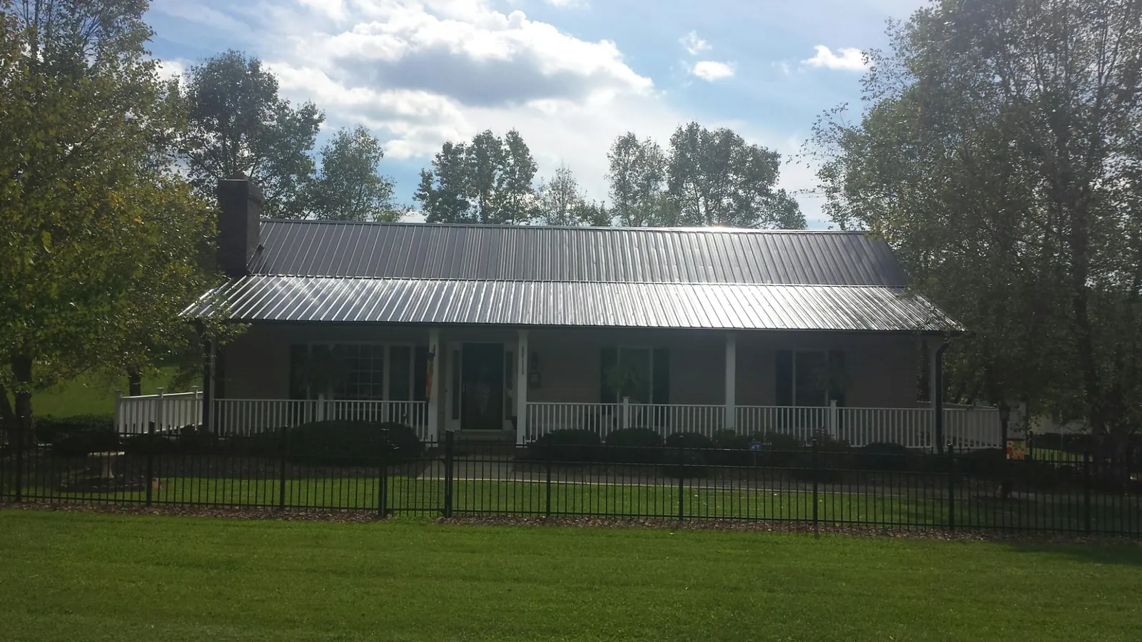 Gray metal roof on a brick ranch with a full width front porch — Gutter Guard Installation work by our crew in Sandown