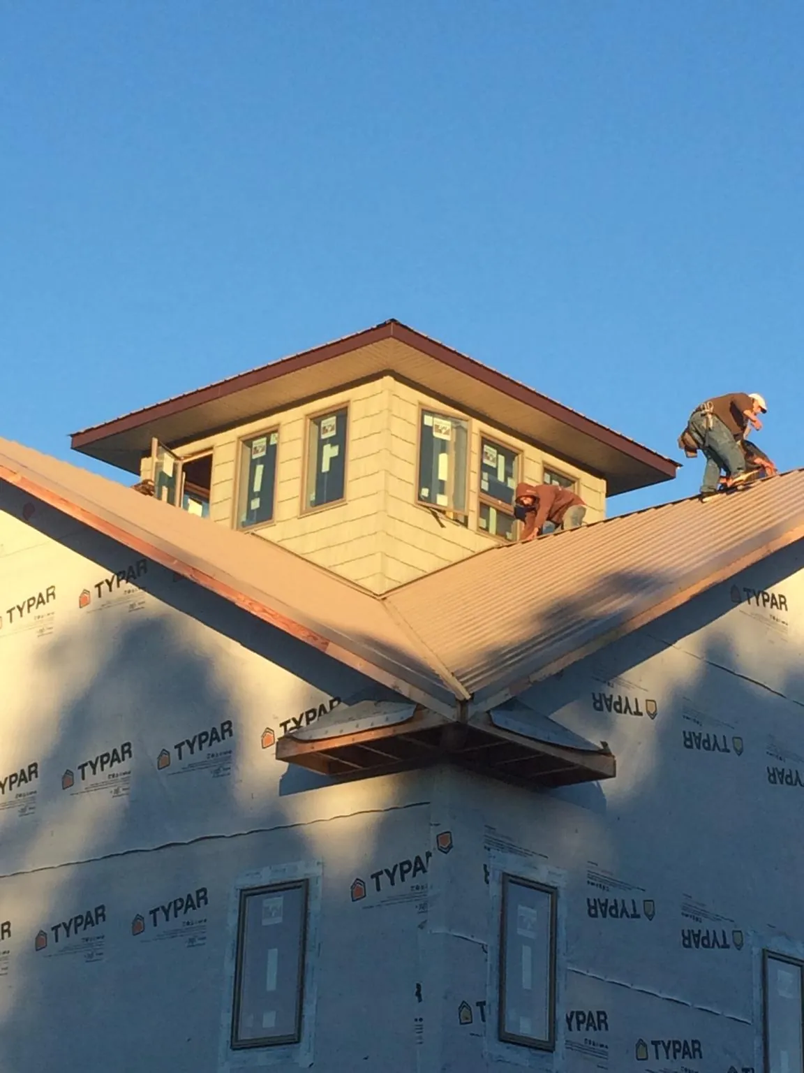Roofers working around a rooftop cupola on a new metal roof at sunset — Roof Waterproofing in Sandown by Roofing Brothers